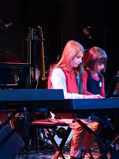 Two of our youngest students sharing a keyboard to perform a duet. We make learning and performing fun and accessible for everyone.