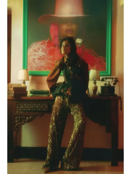 The full look from Chapter 7. The styling combines different textures and eras, with sequined pants and a structured top, set against a modern art piece. This represents a bold, self-defined future.