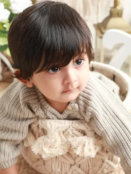 A close-up of a beautiful baby boy with the most amazing hair and expressive eyes. A perfect sitter session portrait.