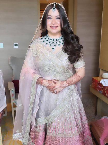 Another beautiful shot of Priyal's contemporary bridal look. The focus is on her radiant skin and the stunning emerald jewelry, which pops against the soft pastel palette.