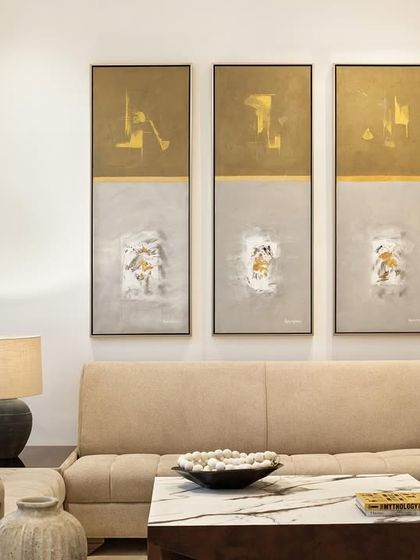 Art and texture bring warmth to the formal living area. Here, a triptych of abstract paintings complements the neutral tones of the sofa and the organic forms of the ceramic vases, creating a composition of quiet sophistication.