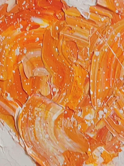 A close-up on the textures of a warm, orange heart. You can see the thick swirls of paint and the delicate white splatters, which add another layer of detail and interest.