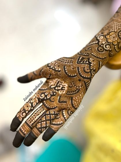 The palm side of Momina's bridal henna, with her initial 'M' elegantly placed in the center.