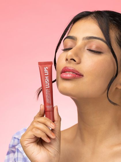 This shot captures a moment of pure bliss. The model's closed eyes and serene expression convey the satisfying feeling of using the product, while the lip gloss itself is held clearly in frame.