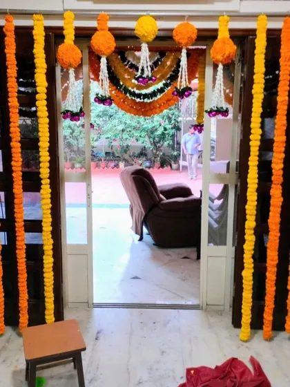 A simple and classic entrance decoration using traditional marigold garlands. The yellow and orange torans create a warm and inviting entryway for a home wedding function.