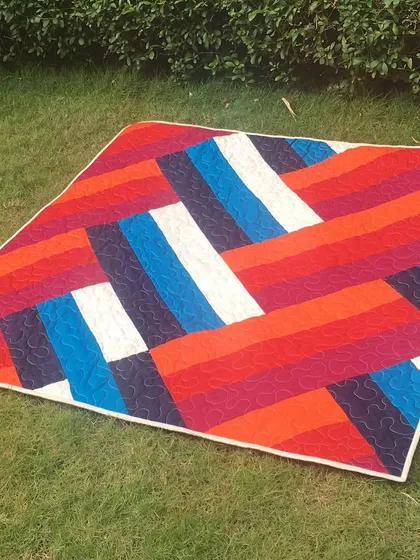 A bright, modern quilt with a bold, graphic pattern of interlocking color blocks.