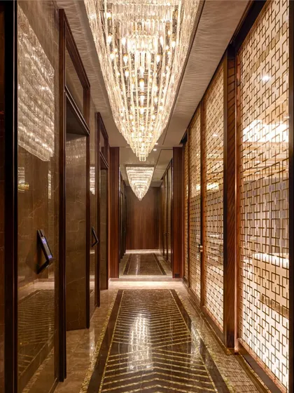 This passageway in our 'Omkar' project is designed to be an experience of sheer opulence. A magnificent 12-foot chandelier illuminates the entrance, reflecting our belief in creating grand, memorable transitions within a home. The intricate floor patterns and rich wooden textures guide the journey into the heart of this majestic residence.