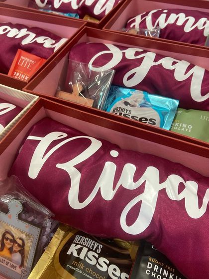 A closer look inside our personalized bridesmaid gift box. Each box contains a custom 'Riya' robe, a personal photo frame, and a selection of chocolates and treats to make her feel truly special.
