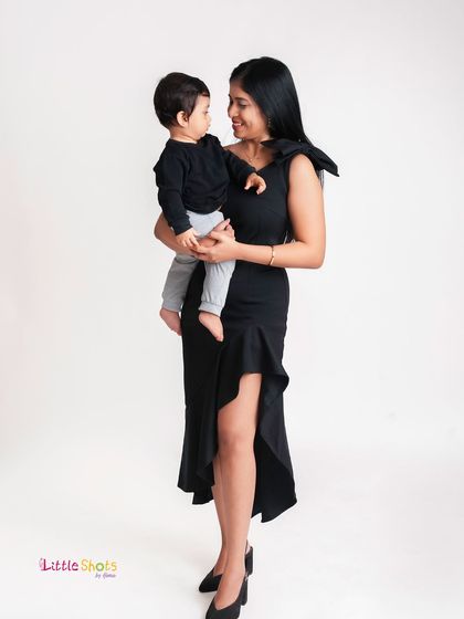 A full-length view of a mother and son in a modern studio setting. The mother's fashionable dress and their sweet interaction make for a very contemporary portrait.