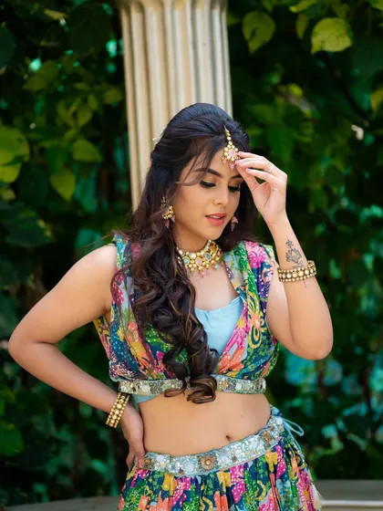 A portrait of a model in a colorful Mehendi outfit. The focus is on her expressive pose and the detailed jewelry, capturing the festive spirit of the occasion.