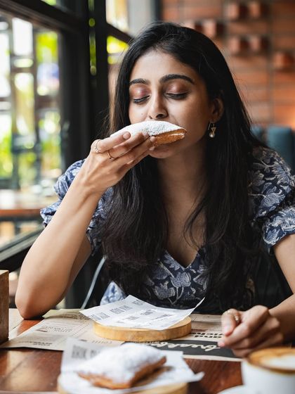 A customer enjoying one of our sourdough beignets, a perfect sweet treat to end a meal or enjoy with coffee.