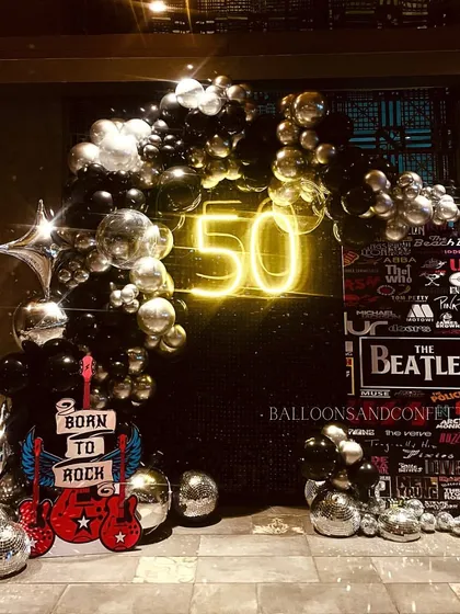 Born to rock. This 50th birthday had a full rock and roll theme, with a black sequin backdrop, a neon '50', and a collage of iconic band logos.