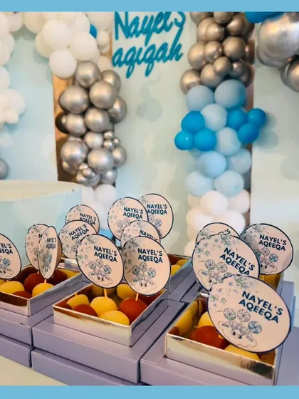 Custom gift boxes we created for an Aqeeqah ceremony. These lavender boxes were filled with sweets and featured personalized toppers with the baby's name, perfectly matching the event's blue and silver decor.