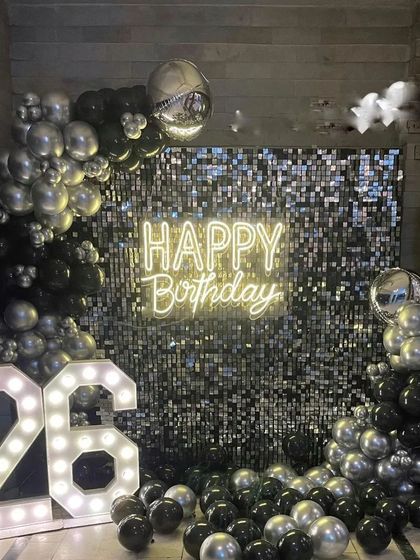 A glamorous 26th birthday with a black and silver sequin wall. The decoration includes a balloon frame, a 'Happy Birthday' neon sign, and large '26' marquee numbers.