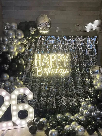 This is another example of a glamorous shimmer wall backdrop, here in a black and silver theme for a 26th milestone. The combination of chrome balloons, a neon sign, and marquee numbers creates a high-energy party atmosphere.