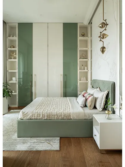 A full view of the sage green bedroom, showing the custom bed, integrated shelving, and 11-foot tall lacquered glass wardrobes. The space is a serene blend of elegance and comfort.