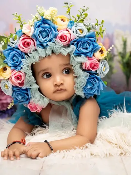 A moment of quiet contemplation. The stunning, colorful floral bonnet frames her face beautifully, drawing all the attention to her soft and curious expression.