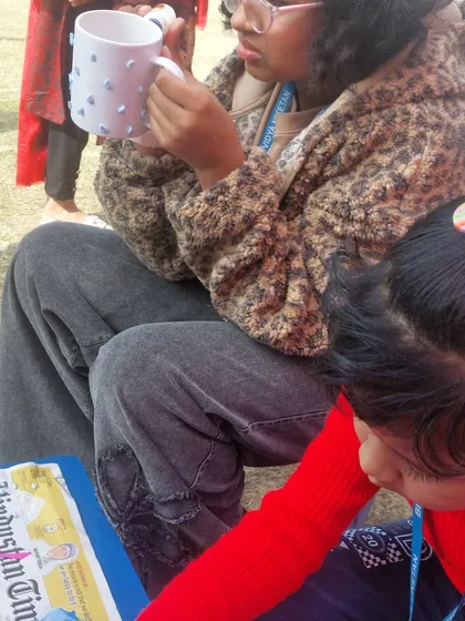 A participant working on her mug at our carnival stall. We guide and assist everyone, ensuring they have a fun and successful creative experience.