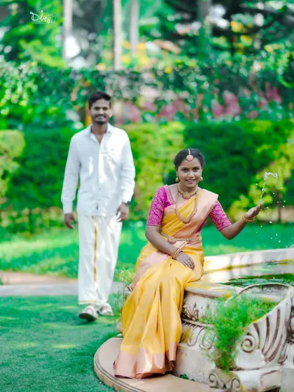 A playful shot in a garden, with the bride sitting by a fountain. This photo captures a candid, happy moment during their traditional pre-wedding shoot.