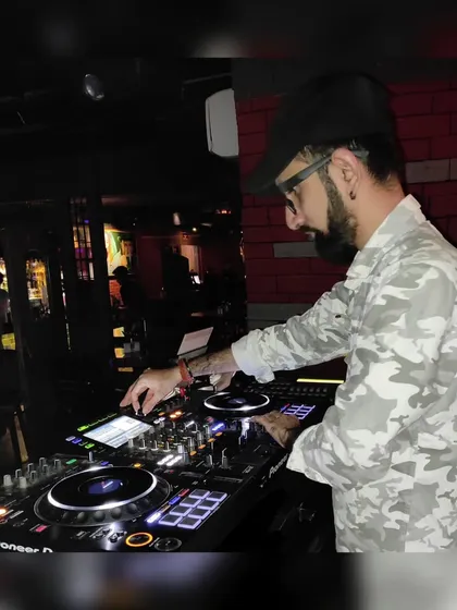 A candid shot of me working the controls in a camouflage shirt during a club night. My focus is always on delivering the best possible sound.
