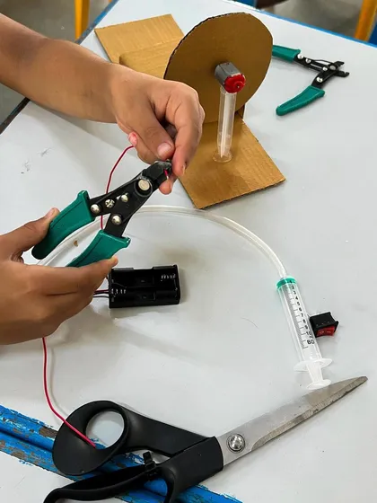 A student uses a wire stripper to prepare the electronics for their disc brake model. Learning to use real tools safely is a core part of my workshops.