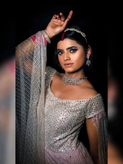 A full-length shot of the coffee-toned glam look. The silver outfit and red bangles create a beautiful contrast.