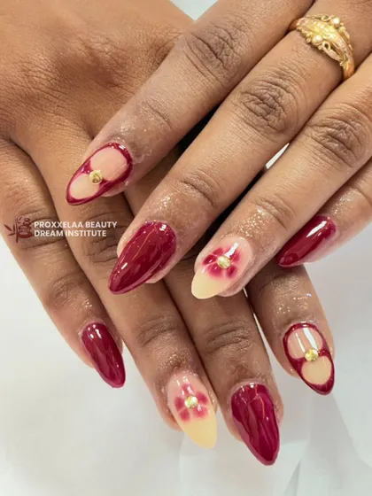 A bold combination of glossy maroon nails and accent nails with floral art and gold studs. This design is perfect for someone who loves rich colors and unique details.
