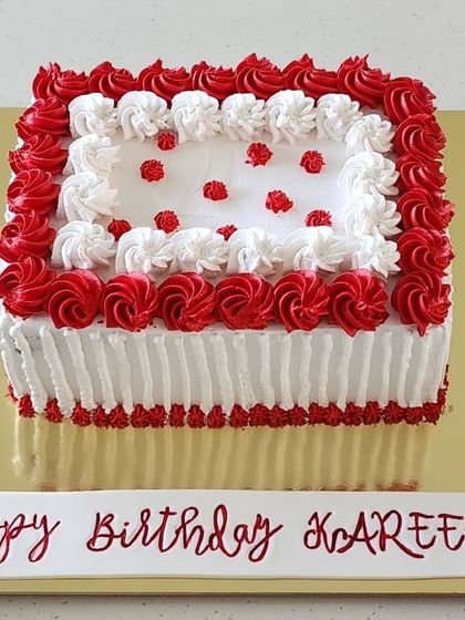 A moist chocolate cake layered with dark chocolate ganache and frosted with silky smooth whipped cream. The red and white piped rosettes give it a classic and elegant look for a birthday celebration.