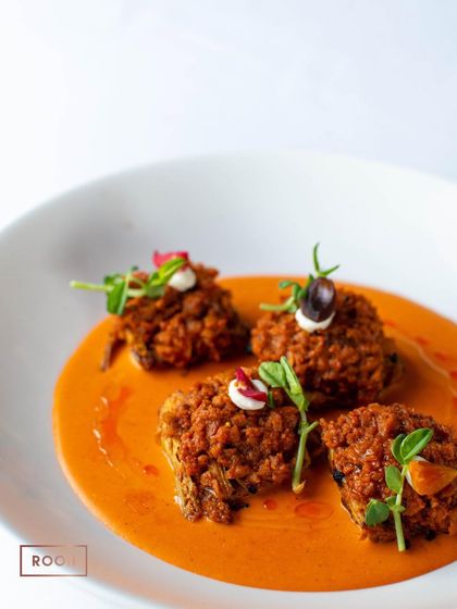 The Achari Artichoke dish, beautifully plated in a rich tomato-based gravy. It's a creative vegetarian option that is full of bold and exciting flavours.