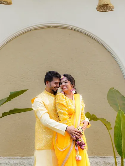 A sweet and happy portrait of a couple during their Haldi ceremony, dressed in matching yellow outfits.