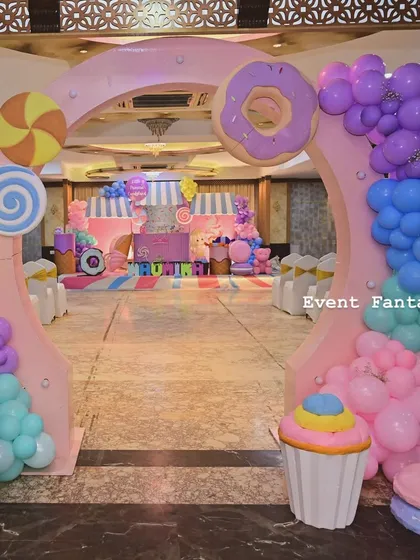 The entrance to Naomika's Candyland, an archway made of giant sweets like donuts and lollipops, with colorful balloon garlands.