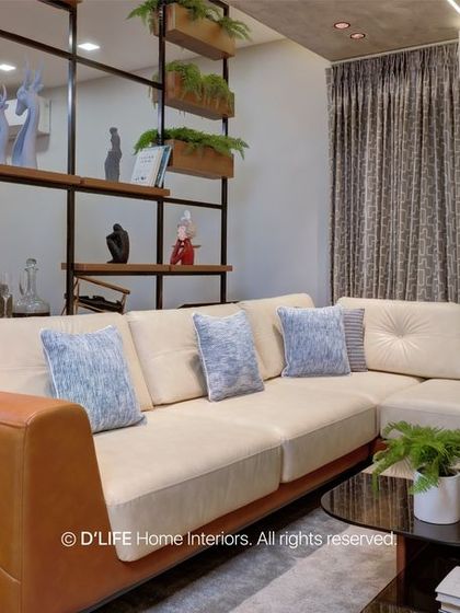 A detail shot of the living room's L-shaped sofa and the open shelving partition that separates the space while maintaining a visual connection to the dining area.