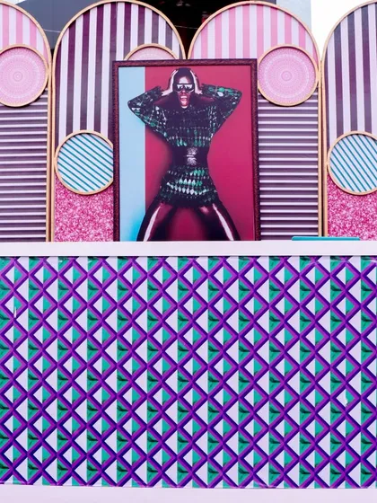 The DJ booth or bar front, decorated with a mix of bold geometric and striped patterns, perfectly capturing the eclectic energy of the Memphis art movement.