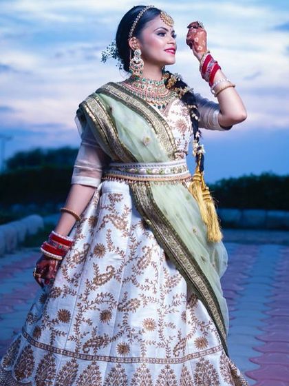 The same white and green lehenga captured against a beautiful evening sky. The belt adds a modern structure to the traditional outfit, highlighting the waist.