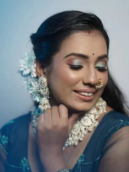 A smiling shot of the model, her eyes sparkling with a beautiful blue and green eyeshadow look.