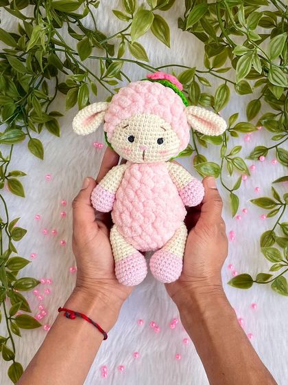 A sweet pink lamb made with a mix of regular and fluffy yarn for a lovely texture. She comes with a removable flower headband.