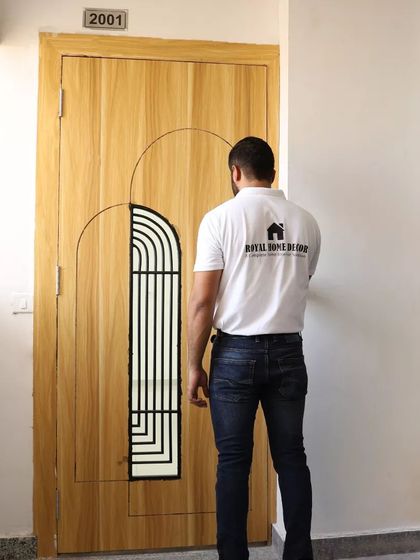 A custom wooden main door with an arched, grilled window insert. The simple, clean design adds a touch of modern elegance to the entrance.