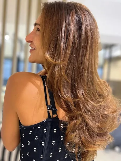 A sun-kissed look achieved with a fresh haircut and color. The layers and highlights work together to create a glossy, healthy, and voluminous style.