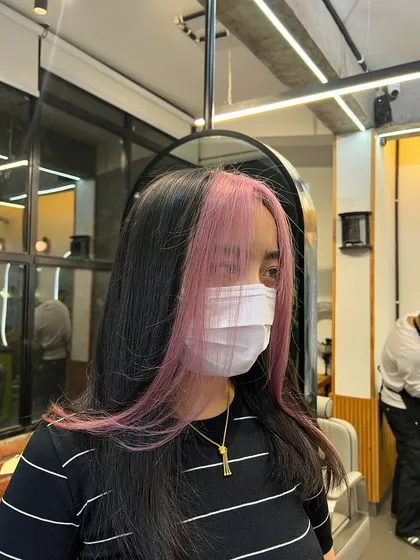 A perfect example of creative color placement. These pastel pink face-framing highlights add a fun, modern twist to a natural base color. It's a great way to express your personality and brighten your features without committing to an all-over color.