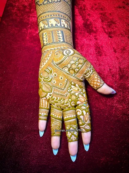 A step-by-step shot of a traditional design, featuring a band of elephants on the wrist and intricate patterns on the palm.