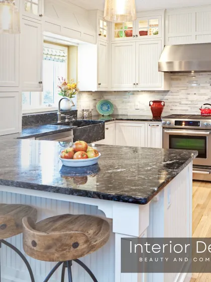 This farmhouse-style kitchen features white cabinetry, a granite countertop, and a large apron sink. The design combines traditional charm with modern functionality, including a breakfast bar for casual meals.