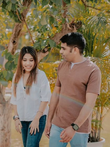 A candid walking shot of a couple in a beautiful garden setting. The natural light and relaxed posture create an authentic and heartwarming portrait.