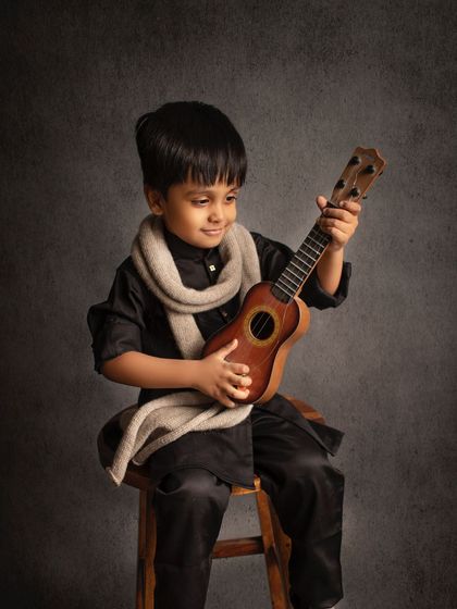 A little rockstar in the making! This classic portrait captures his cool and confident personality as he strums a ukulele.