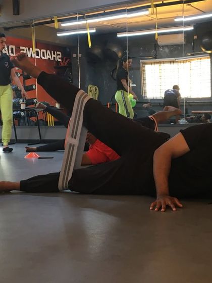 A student performs a side-lying leg lift with a resistance band, learning to isolate and strengthen the gluteus medius.