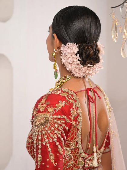 For this bride, I used soft pink hydrangea to create a full, romantic frame around her twisted bun. The color beautifully complemented the embroidery on her red lehenga.