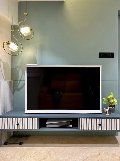 A simple and statement TV wall for an entertainment room. The floating console and minimalist design keep the focus on the screen, while the unique pendant light adds a sculptural element.