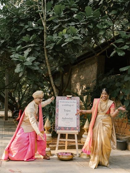A fun and happy welcome! A couple playfully gestures towards their wedding sign, inviting guests to join in their celebration.