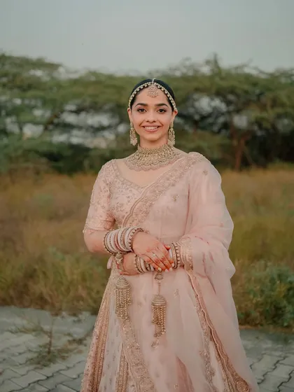 A full-length shot of the bride in her stunning blush pink lehenga. The look is soft, radiant, and perfectly suited for a modern bride.