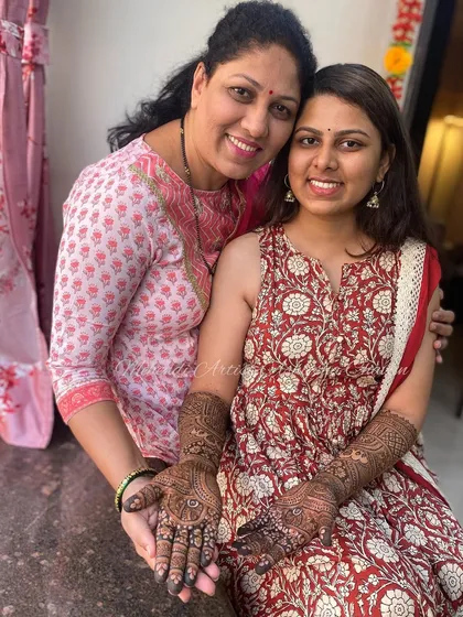 A heartwarming photo of a bride with her mother, both sharing a moment of love. The bride's intricate engagement mehendi is beautifully displayed.