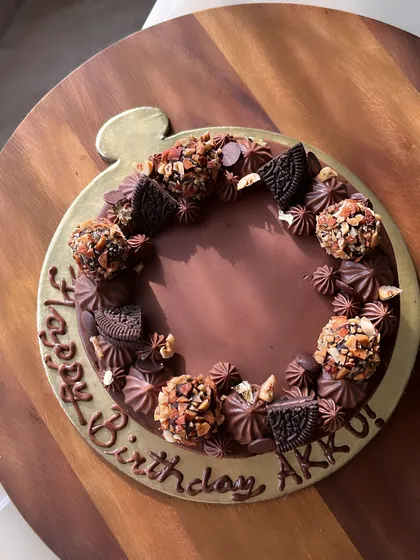 Our Majestic Chocolate Cake, decorated for a birthday. It's covered in a rich dark chocolate ganache and adorned with roasted almond truffles.
